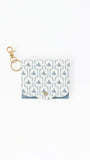A small white card holder or pouch with a blue damask pattern, featuring a gold-tone metal clasp and key ring attachment, set against a plain white background.