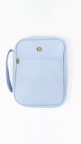 A light blue faux-leather bible cover with a front zippered pocket and a small gold-tone logo charm, shown on a plain white background.