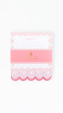A pink and white to-do list notepad with decorative lace and striped borders, a pink center band with gold foil lettering, and a scalloped bottom edge, photographed on a clean white background.