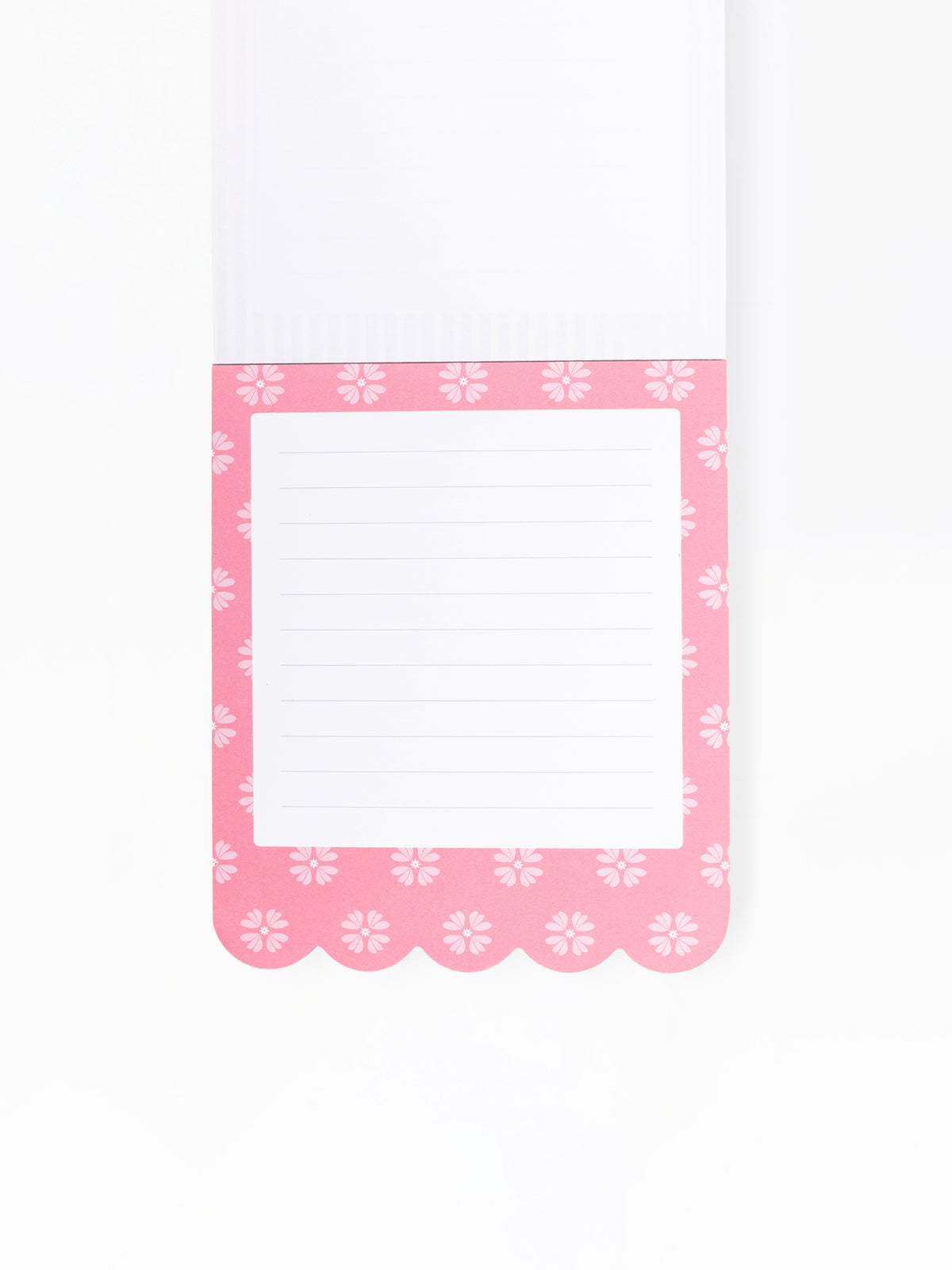 A close-up of a lined notepad page with a pink border decorated with a repeating white floral pattern and scalloped edges, shown on a white background.