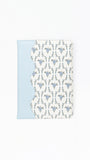 A notebook featuring a light blue side panel and a white front cover with a repeating blue ornamental pattern, shown on a plain white background.