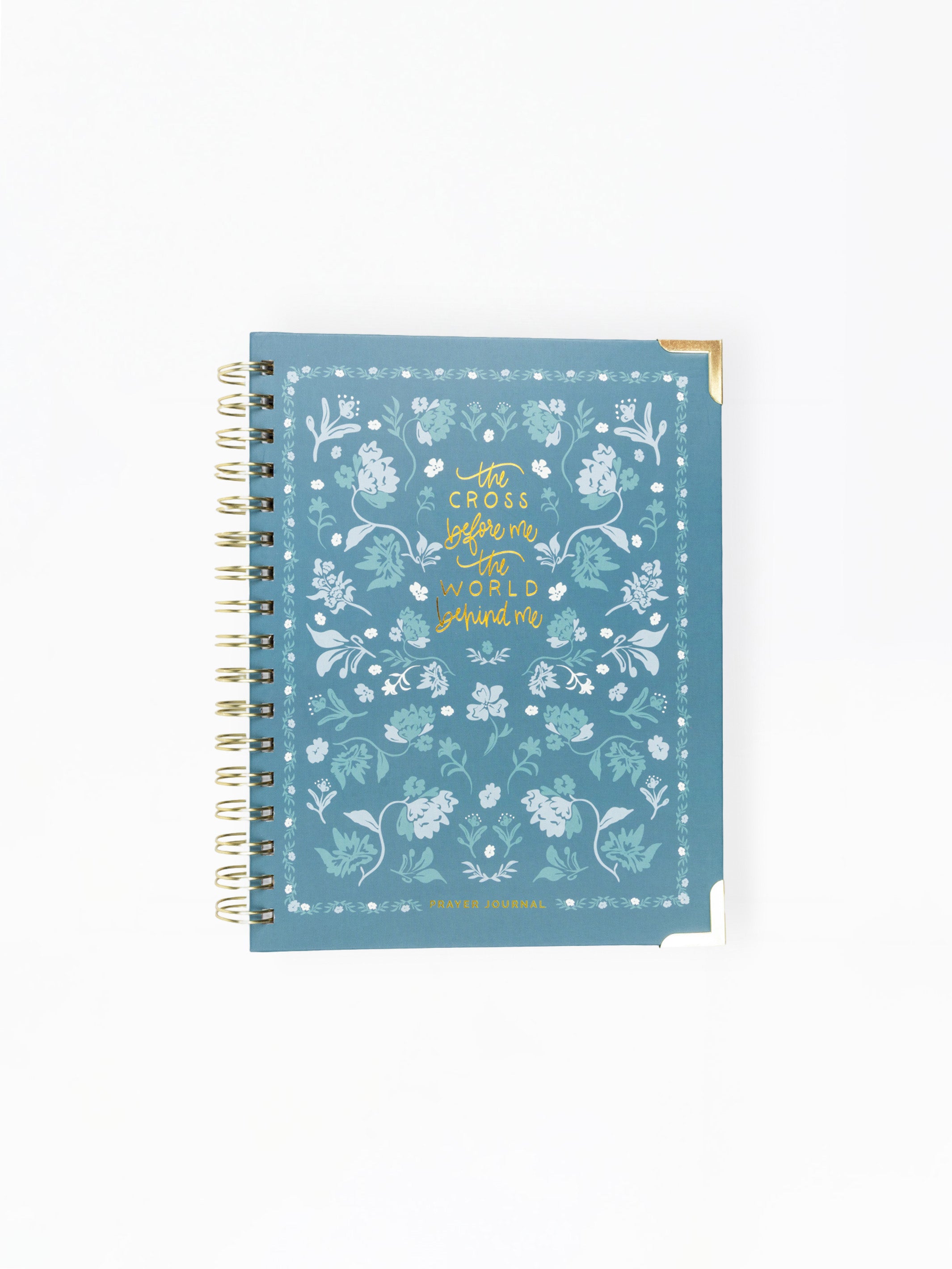 A spiral-bound notebook with a dusty blue cover decorated with white floral patterns and gold foil text reading 'with courage before me and hope behind me'.