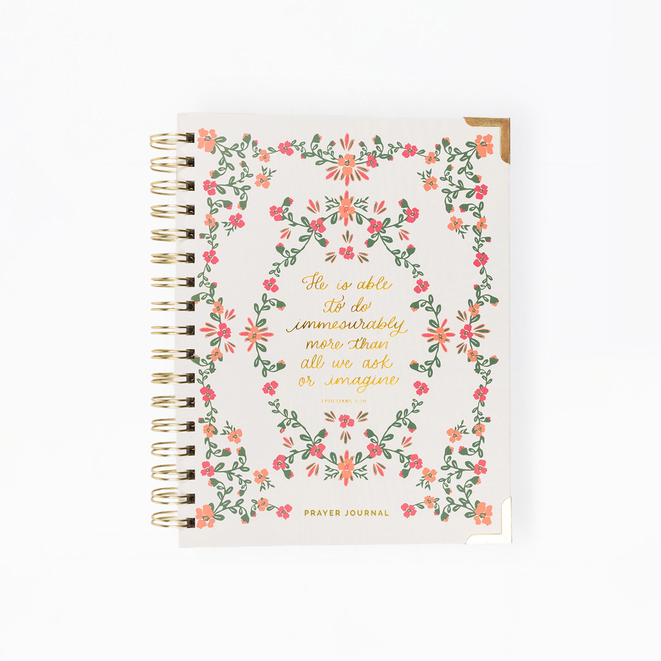 A spiral-bound prayer journal with a cream-colored cover decorated with a pink and green floral wreath and gold foil lettering, shown on a plain white background.