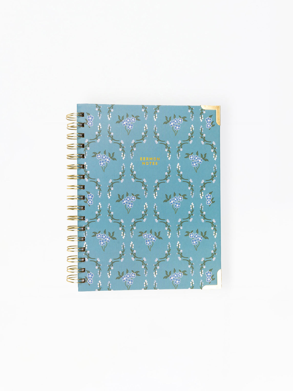 A spiral-bound planner or notebook with a dusty blue cover featuring a repeating white and purple floral pattern, shown on a plain white background.