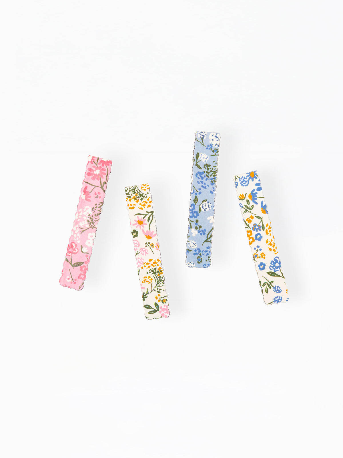 Four slim rectangular hair clips with delicate floral patterns in pink, yellow, blue, and white, arranged vertically on a plain white background.