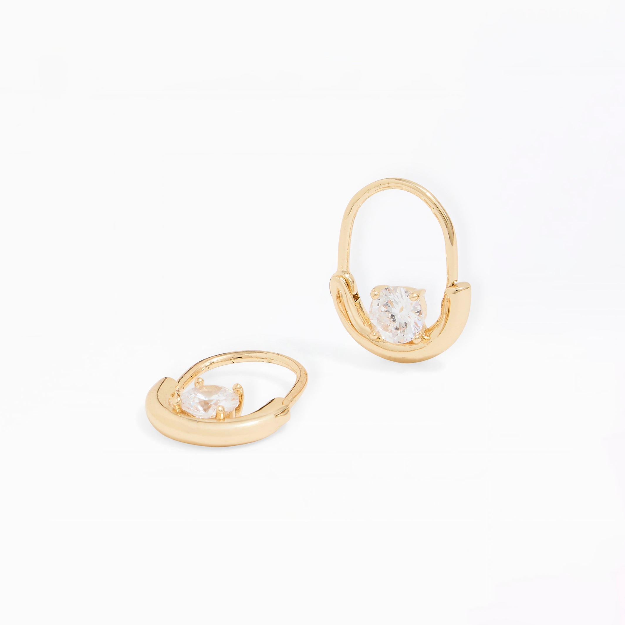 A pair of gold huggie hoop earrings with a clear heart-shaped crystal in the center, displayed on a clean white background.