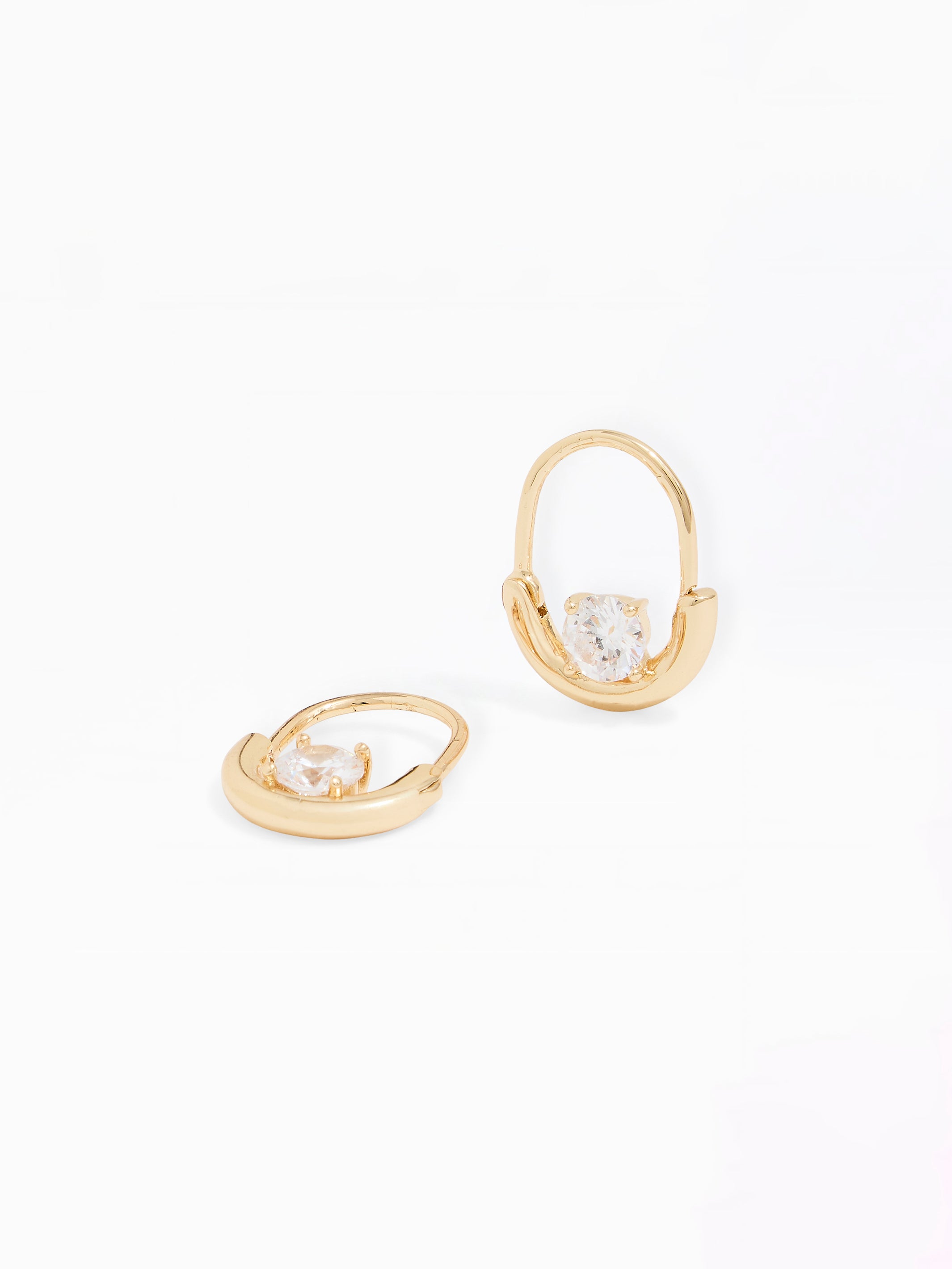 A pair of gold huggie hoop earrings with a clear heart-shaped crystal in the center, displayed on a clean white background.