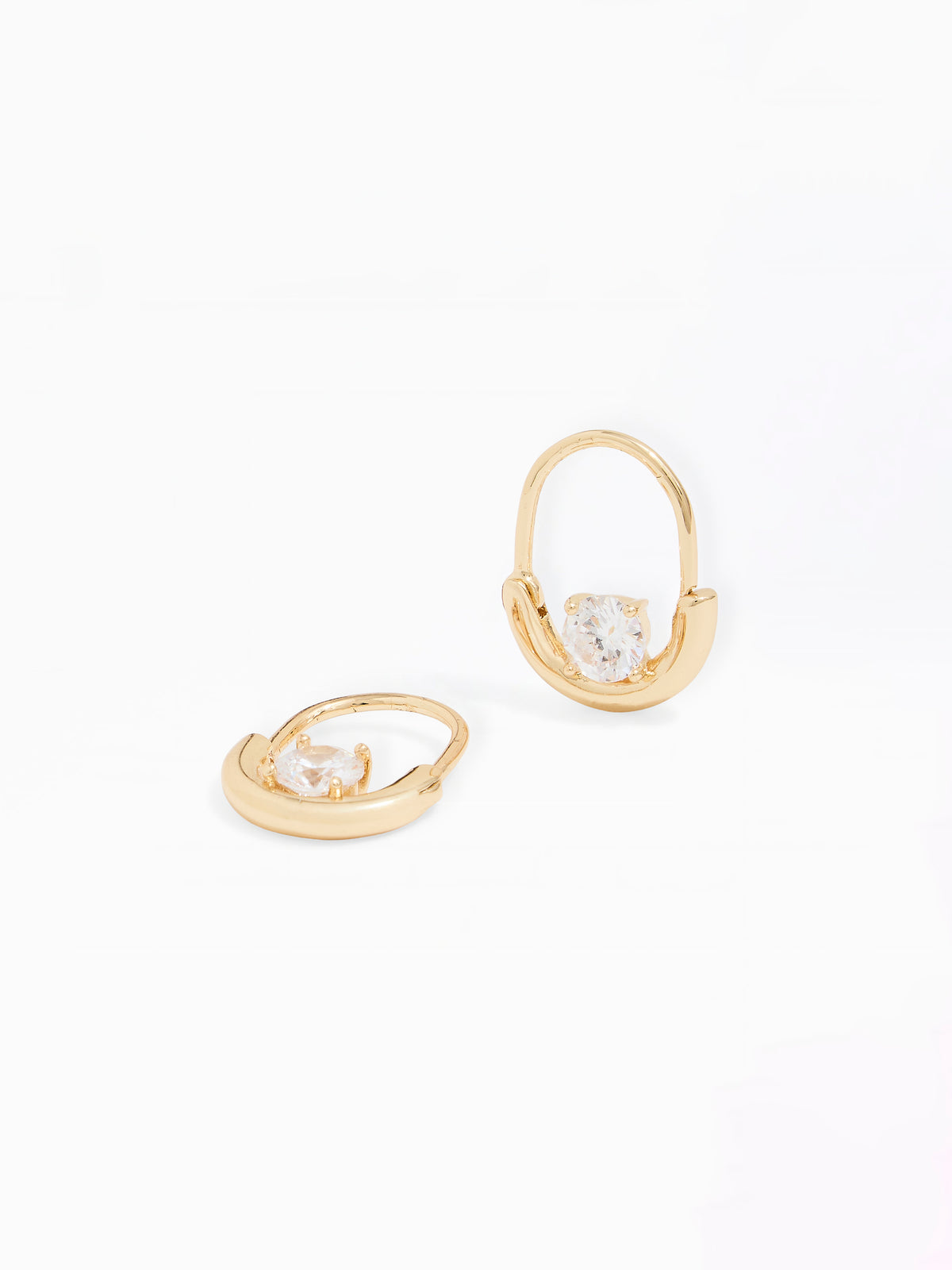 A pair of gold huggie hoop earrings with a clear heart-shaped crystal in the center, displayed on a clean white background.