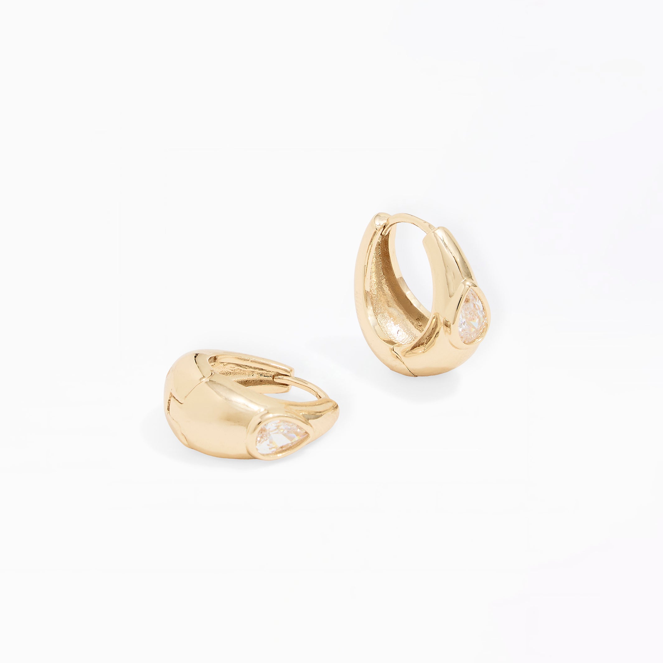 A pair of gold huggie hoop earrings with small clear gemstone accents, displayed on a clean white background.
