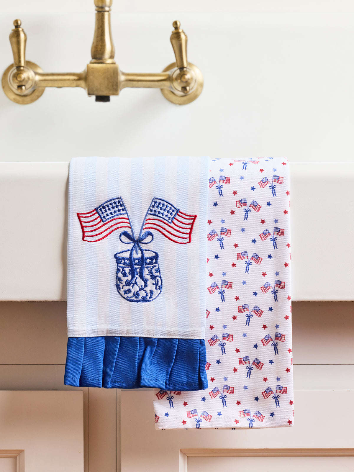Two decorative towels with American flag designs hanging on a kitchen towel rack.