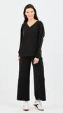 Woman wearing a black outfit with wide-leg pants on a white background