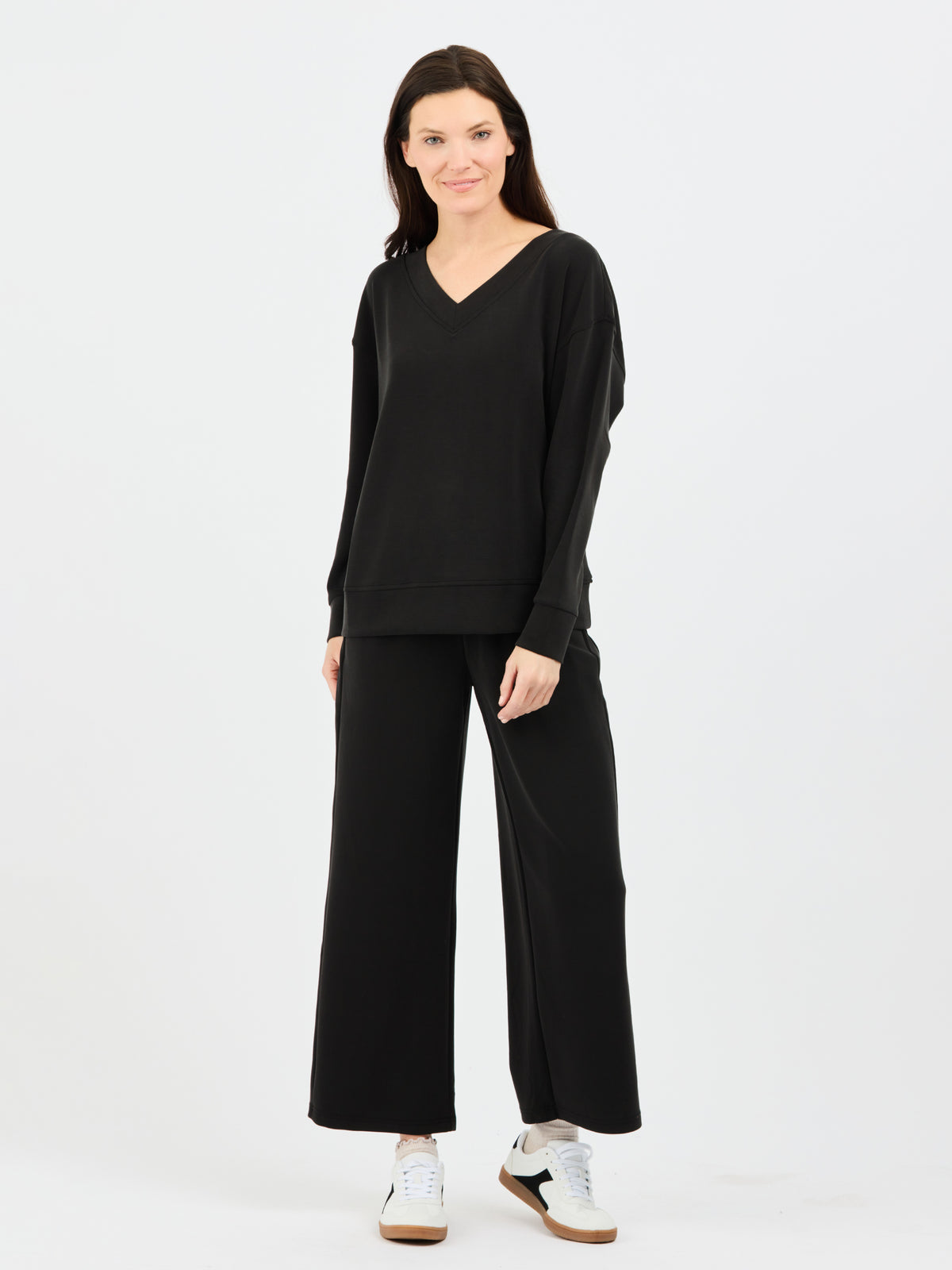 Woman wearing a black outfit with wide-leg pants on a white background