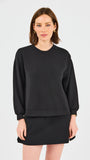 Woman wearing a black sweatshirt and skirt set on a white background