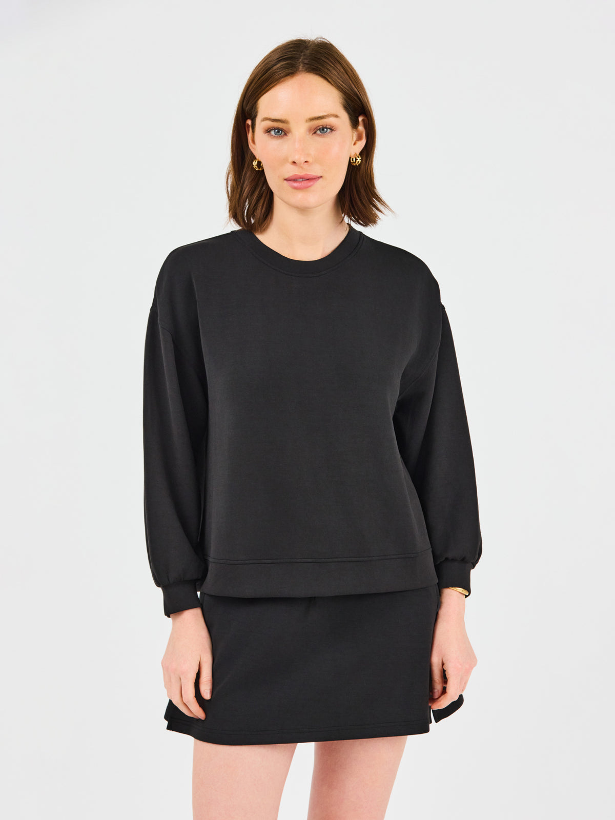 Woman wearing a black sweatshirt and skirt set on a white background