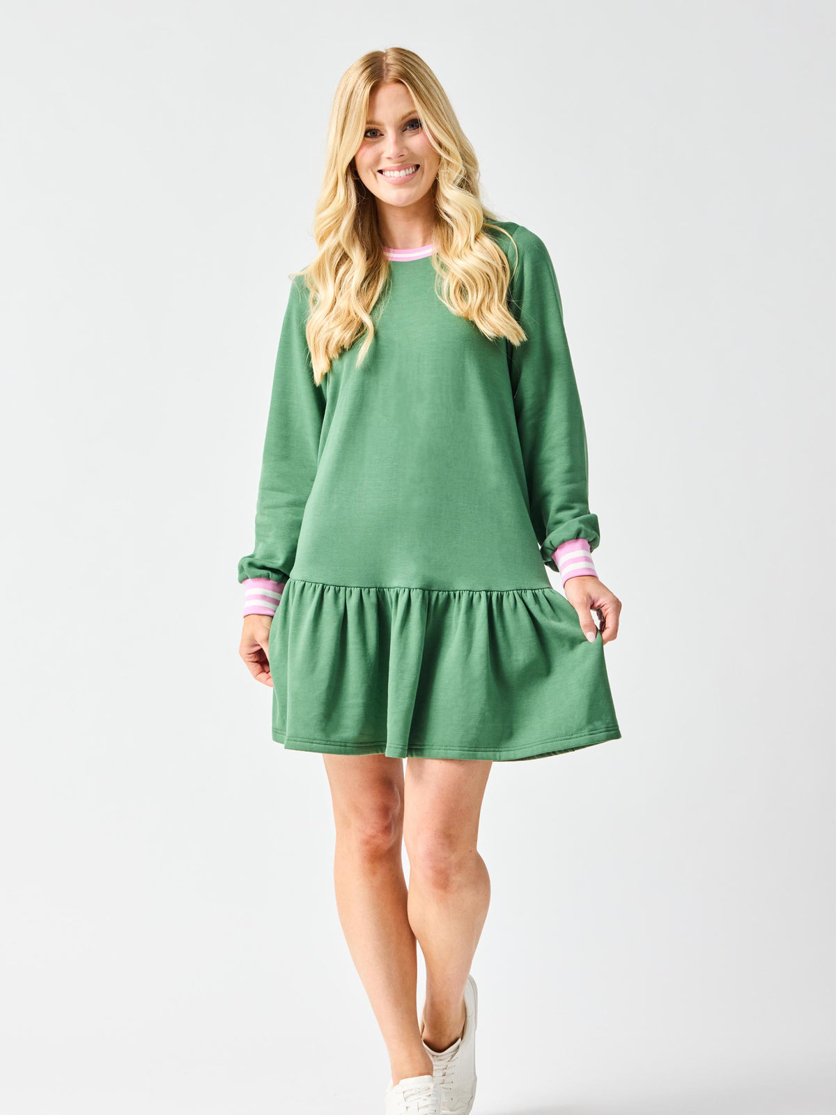 Woman wearing a green dress with pink trim on a plain background