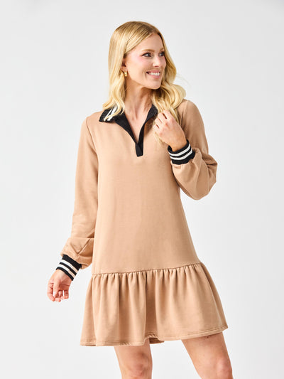 Woman wearing a beige dress with black and white striped cuffs on a white background