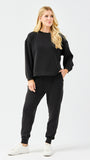 Woman wearing a black outfit with white sneakers on a white background
