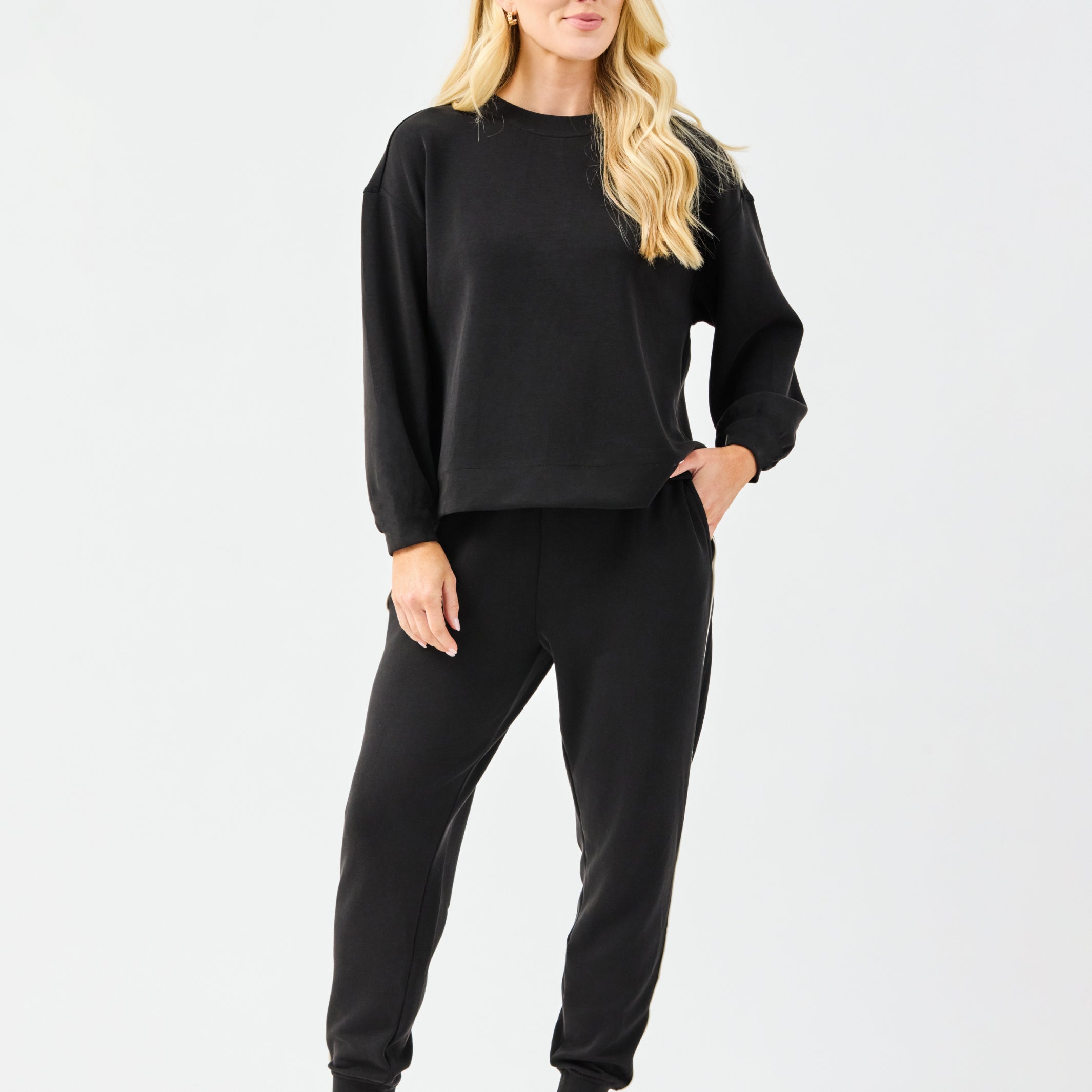 Woman wearing a black outfit with white sneakers on a white background