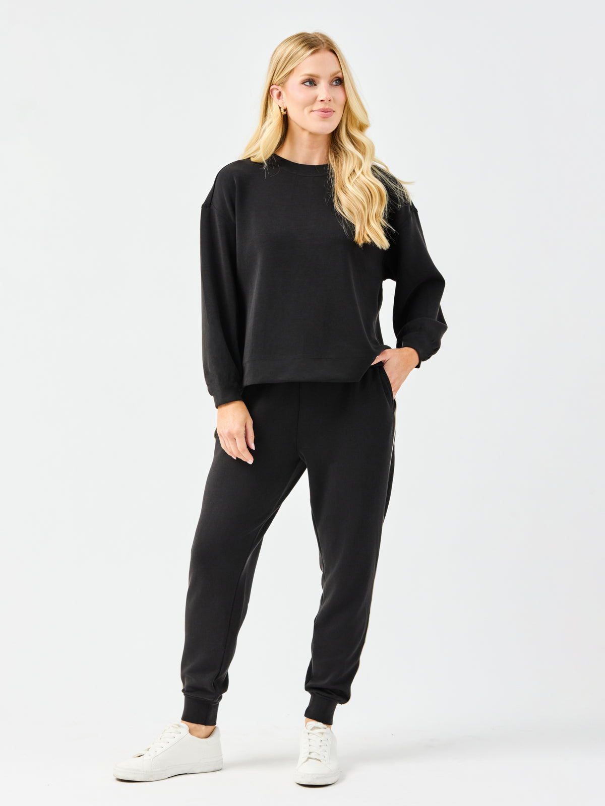 Woman wearing a black outfit with white sneakers on a white background