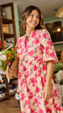Woman wearing a  pink floral midi dress holding flowers